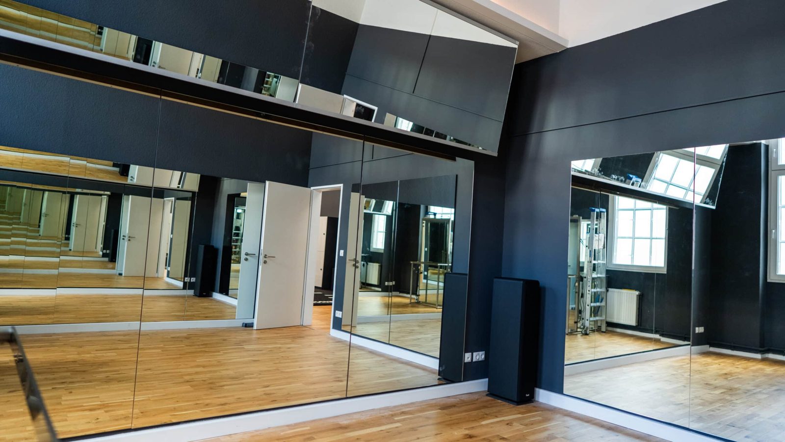 Posing-Raum mit großer Spiegelwand, Holzboden und justierbarem Licht im Invictus Gym Hamburg