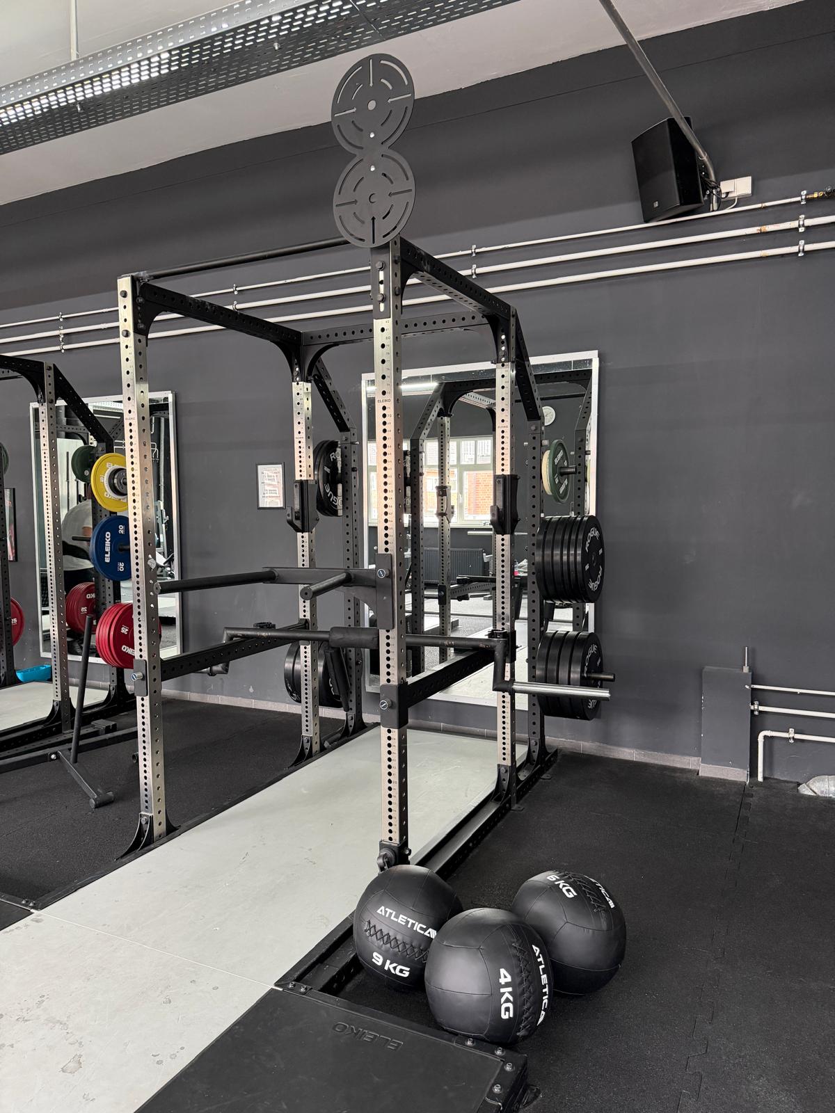 Power Rack mit Safety Bars, Hantelscheiben und Wall-Ball-Zielscheibe im Functional-Fitness-Bereich des Invictus Gym Hamburg Bergedorf